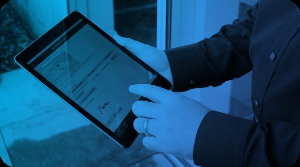 A hand signing a form on a tablet using the FlowForma Mobile App